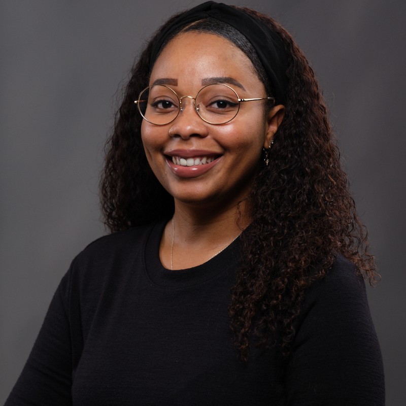 A professional photo of a woman in a black sweater and glasses.