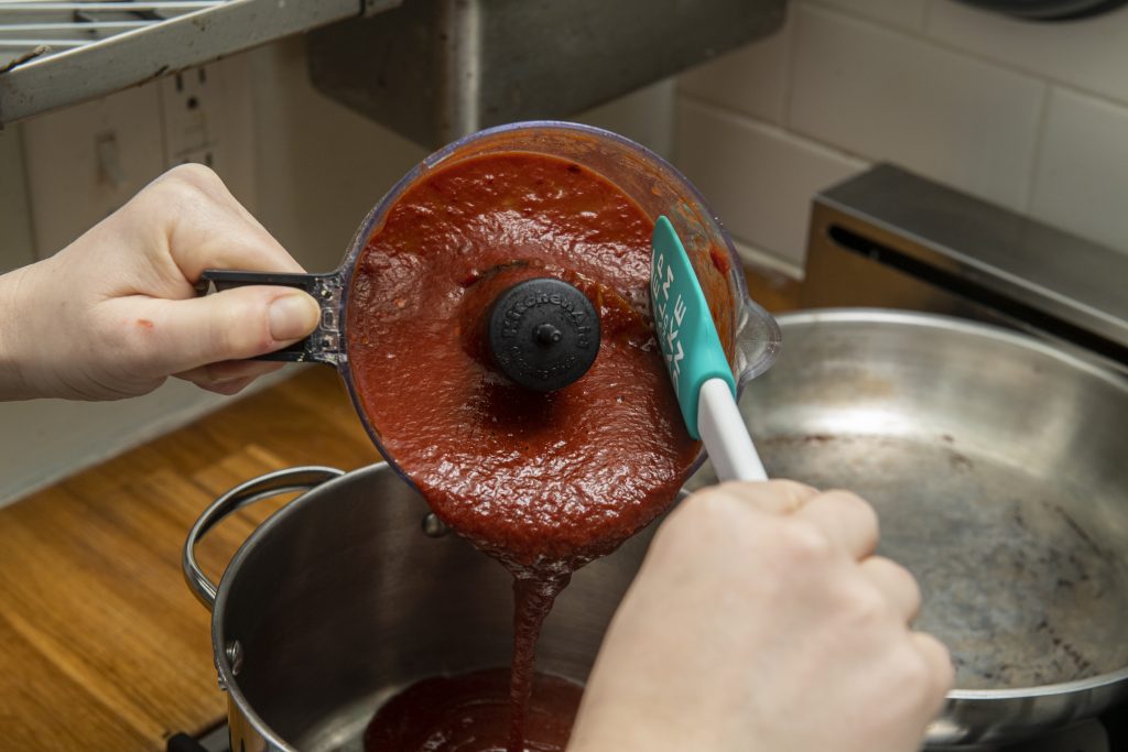 BBQ sauce being poured from a food processor into a saucepan