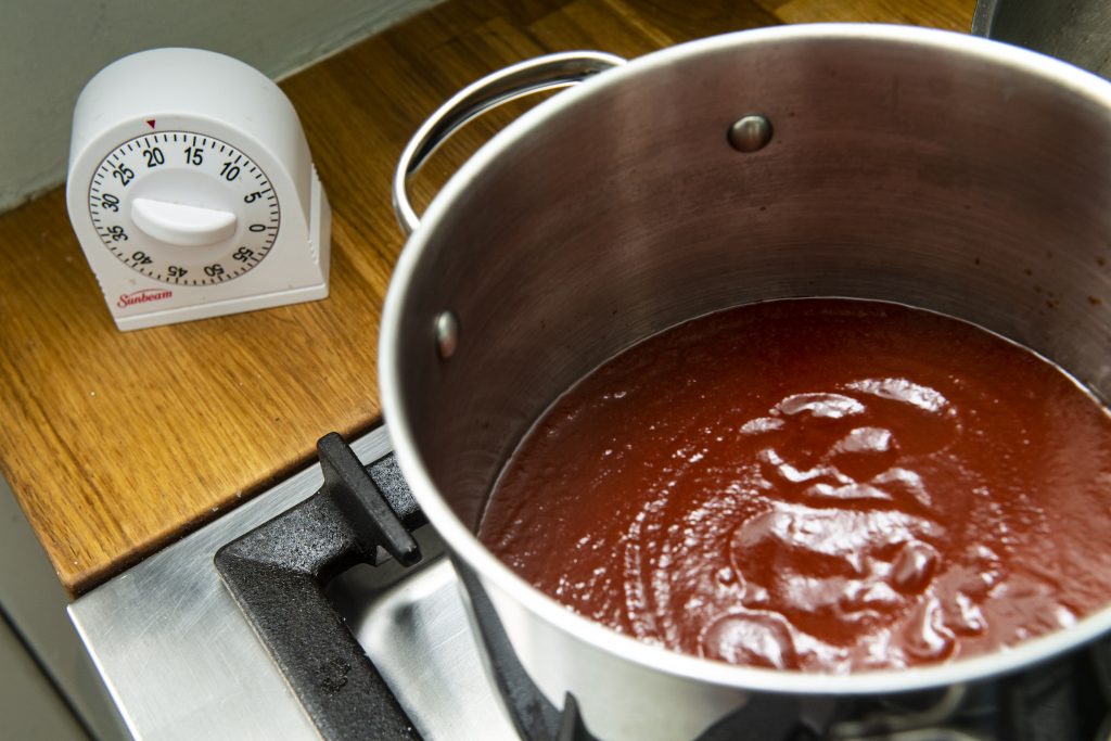 BBQ sauce in a saucepan next to a kitchen timer set to 20 minutes