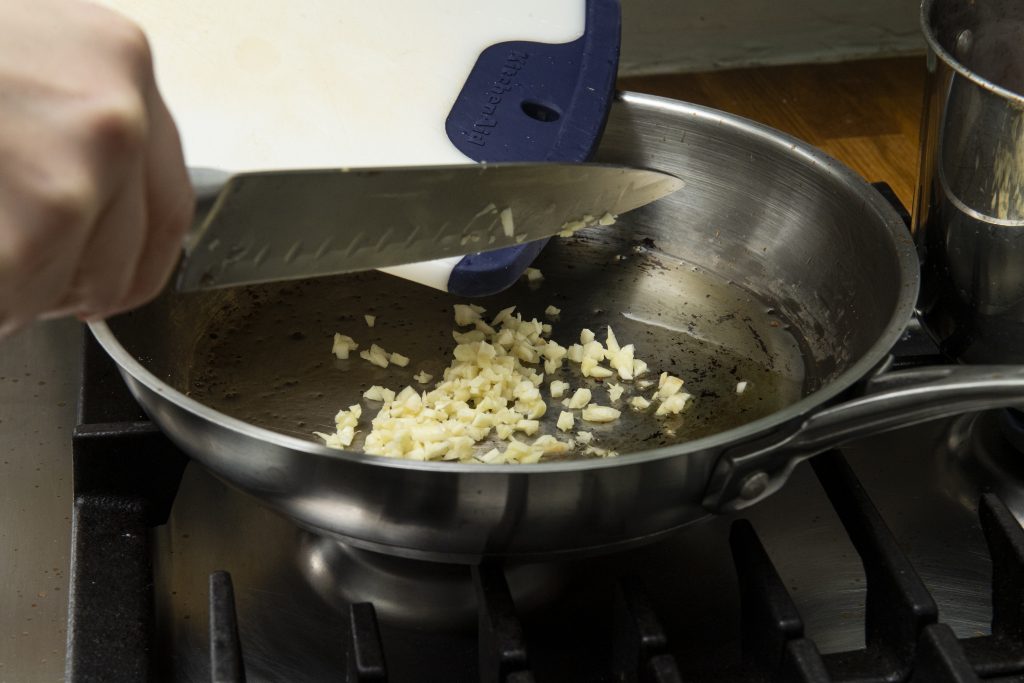 Chopped garlic being added to a pan