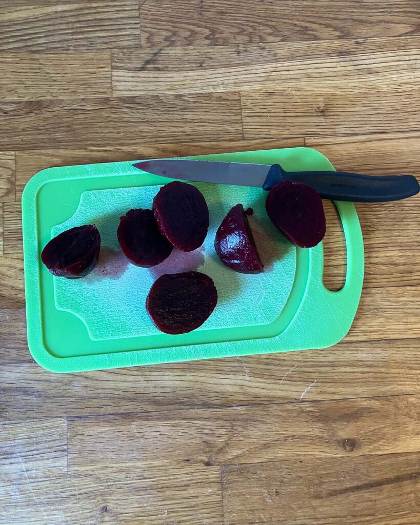 Three beets sliced lengthwise on a cutting board 