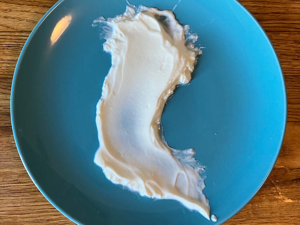 A decorative smear of white yogurt on a blue plate.