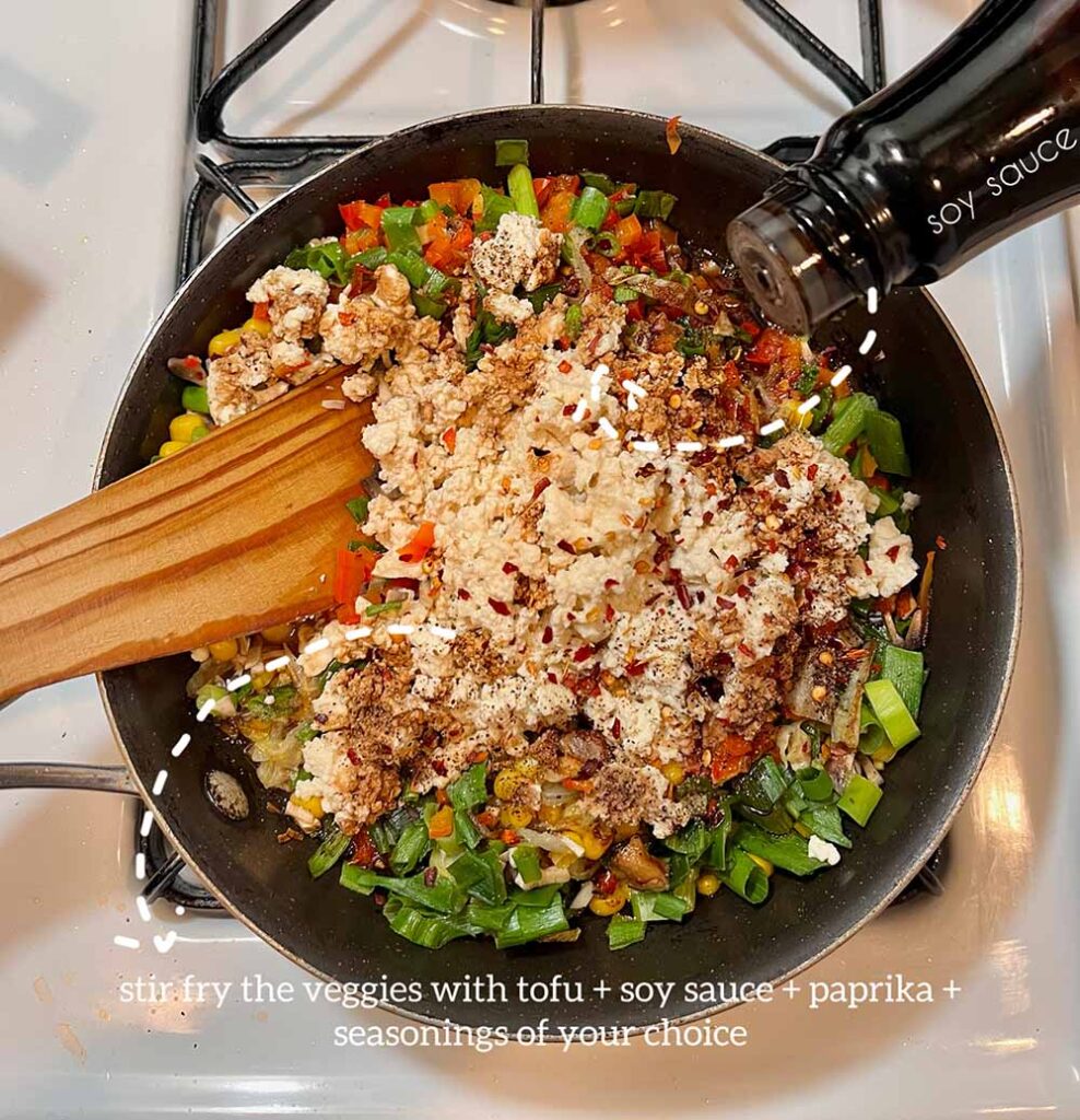 Chopped vegetables and tofu in a frying pan on a stove, being stirred by a wooden spoon. Someone is adding soy sauce to the pan. Captions label the soy sauce and say "Stir fry the veggies with tofu + soy sauce + paprika + seasonings of your choice."